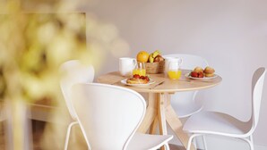 A breakfast table with a basket of fruits, two plates with muffins and strawberries, and two glasses of orange juice. - MH Apartments Blasco Valencia (Valencia)