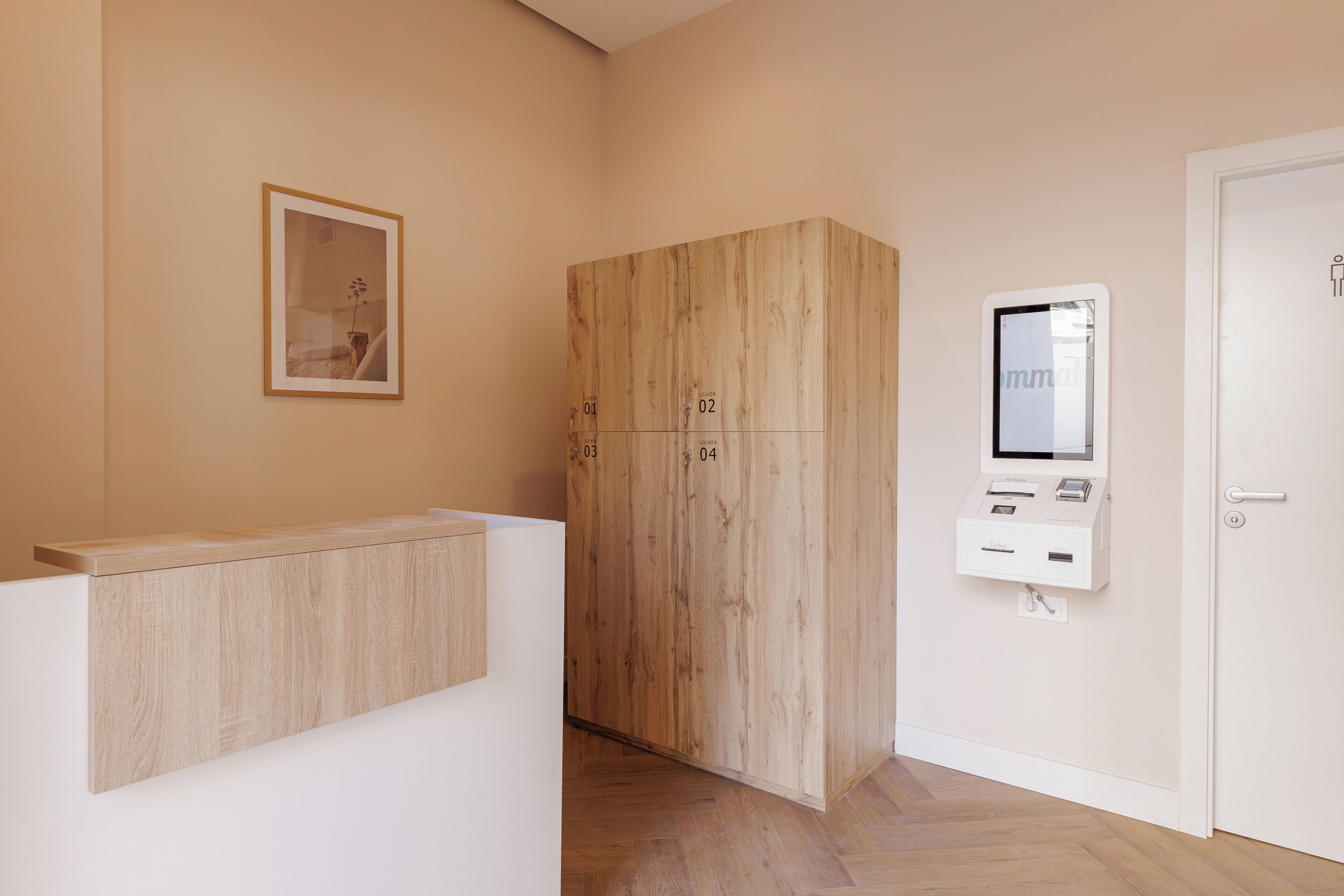 A reception area with a wooden cabinet, a framed picture, and a digital kiosk.