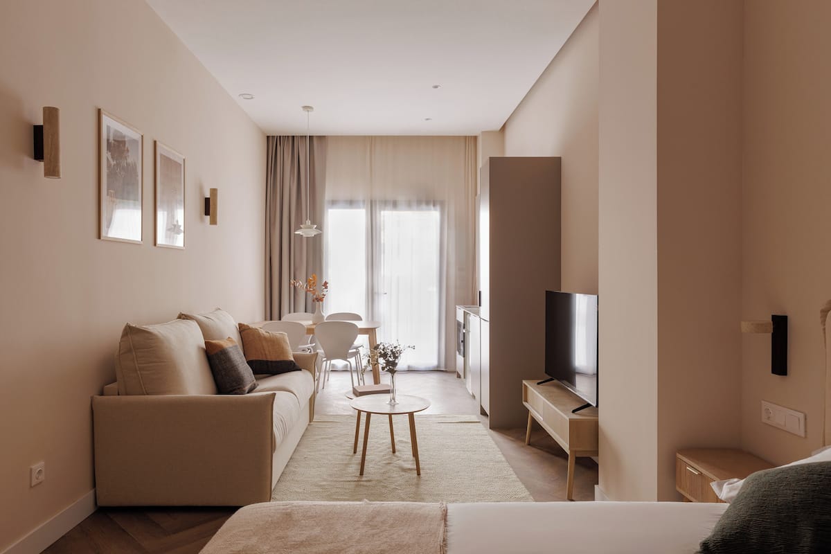 Une chambre d’hôtel moderne avec un canapé, une petite table ronde, un téléviseur et une grande fenêtre.