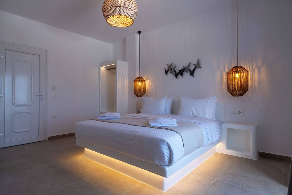 Une chambre à coucher moderne avec un grand lit, des tables de chevet et des œuvres d’art décoratives au mur.