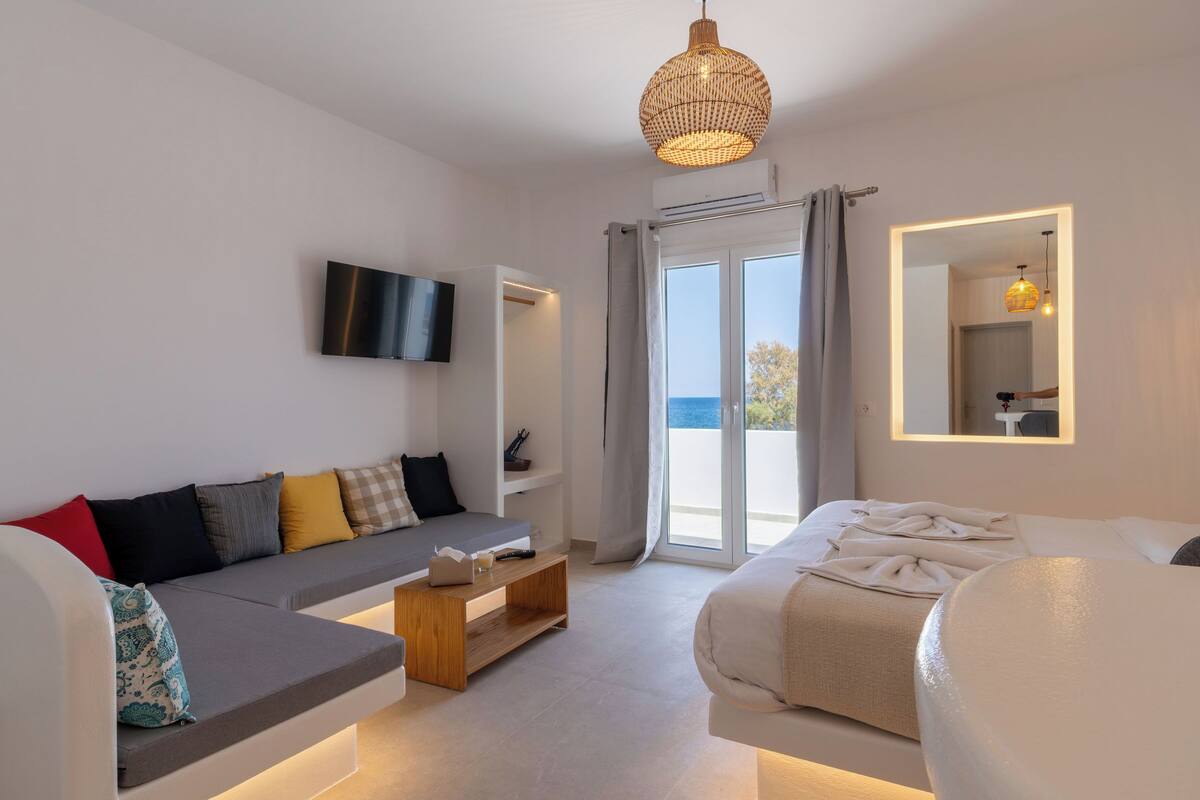 Une chambre d’hôtel moderne équipée d’un canapé, d’un lit, d’une télévision et d’une grande fenêtre donnant sur un beau paysage.