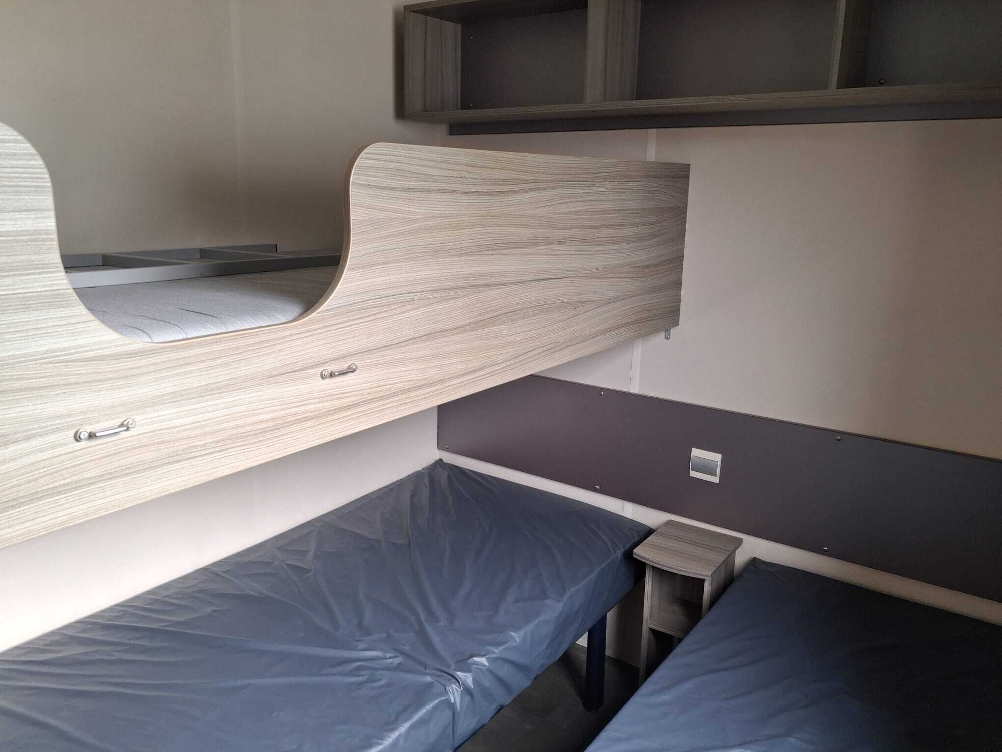 A bunk bed with a wooden headboard and a small bedside table.