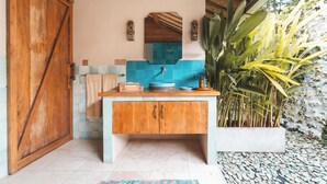 A bathroom with a wooden door, a sink with a blue tile backsplash, and a large plant. - Deluxe Room with Pool Access (Uluwatu)