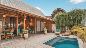 A wooden building with a pool, outdoor seating, and potted plants. - Deluxe Room with Pool Access (Uluwatu)