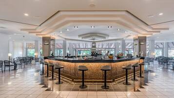 A spacious bar area with a central island, multiple stools, and a tiled floor.