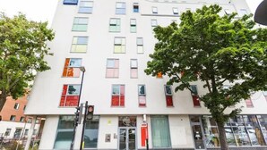 A modern building with multiple windows, a visible entrance, and a tree in front. - Islington 2 (London)