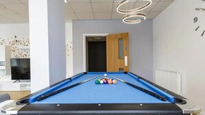 A pool table with balls, a television, and a door leading to another room. - Islington 2 (London)