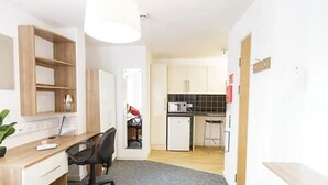 A compact room with a desk, chair, and kitchenette. - Islington 2 (London)