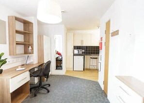 A compact room with a desk, chair, and kitchenette. - Islington 2 (London)