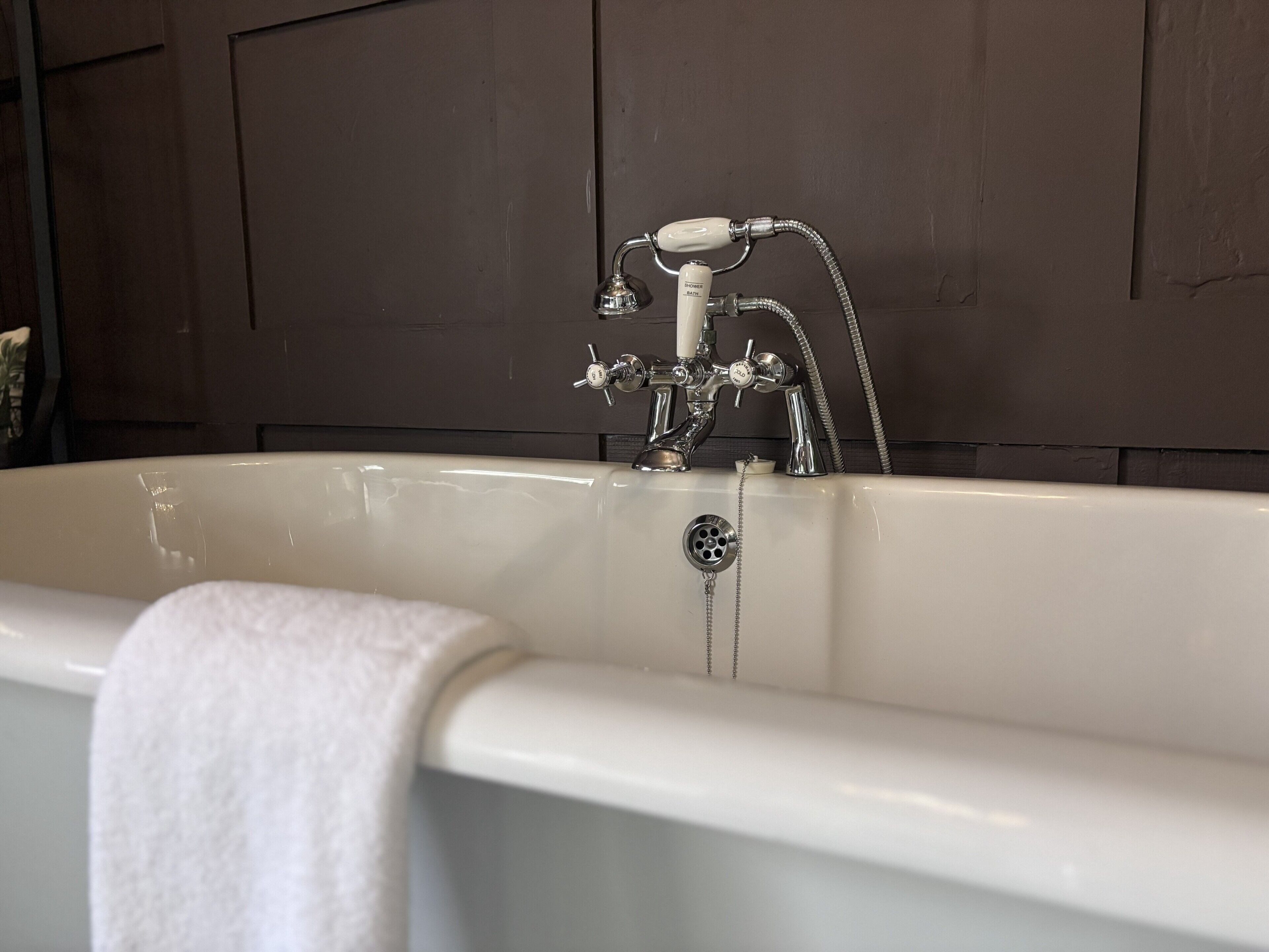 A bathtub with a shower head, a faucet, and a drain.
