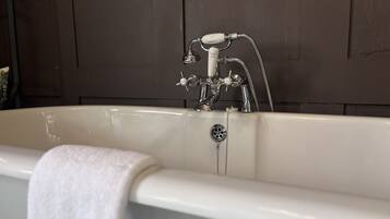 A bathtub with a shower head, a faucet, and a drain.