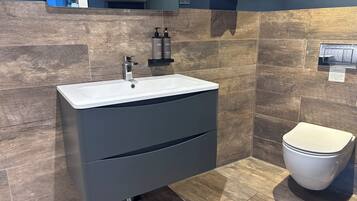A modern bathroom with a white sink, dark cabinetry, and a toilet.