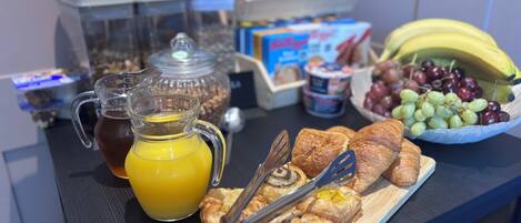 A breakfast buffet with pastries, a pitcher of orange juice, and a bowl of grapes.
