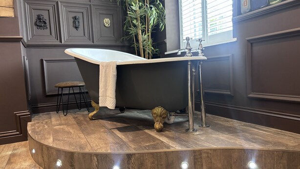 Un baño moderno con una bañera independiente, un tocador de madera y una planta en maceta.