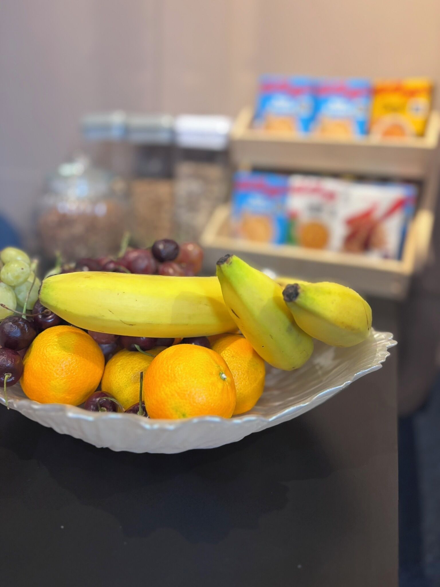 Un saladier rempli de fruits, notamment des bananes, des oranges et des raisins.
