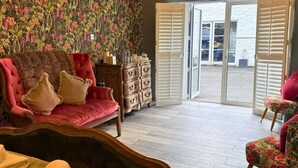 Una habitación con un sofá rojo, un armario de madera y vistas a un área exterior a través de puertas abiertas.