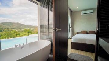 A modern bathroom with a large bathtub, a shower, and a view of a mountainous landscape.