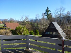 Ein Holzzaun, ein Haus mit geneigtem Dach und ein Nadelbaum.