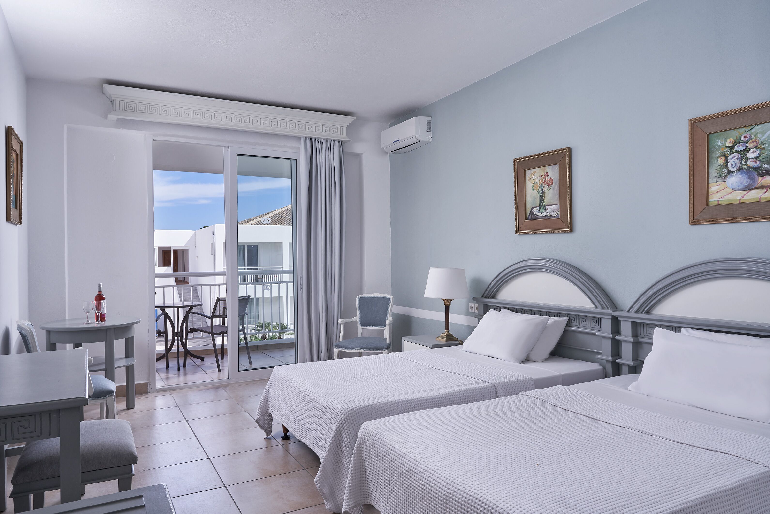 Une chambre d’hôtel avec deux lits, un balcon, un coin repas et une vue sur l’extérieur.