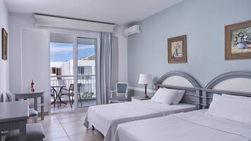 Une chambre d’hôtel avec deux lits, un balcon, un coin repas et une vue sur l’extérieur.