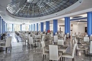 Un comedor interior amplio con techo alto y ventanas grandes.