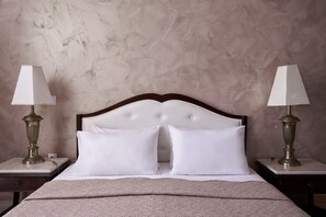 A neatly made bed with white linens, two bedside tables with lamps, and a textured wall. - Sandy Beach Resort (Corfu)