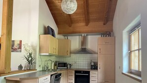 Een keuken met houten balken, een magnetron, fornuis en een spoelbak.