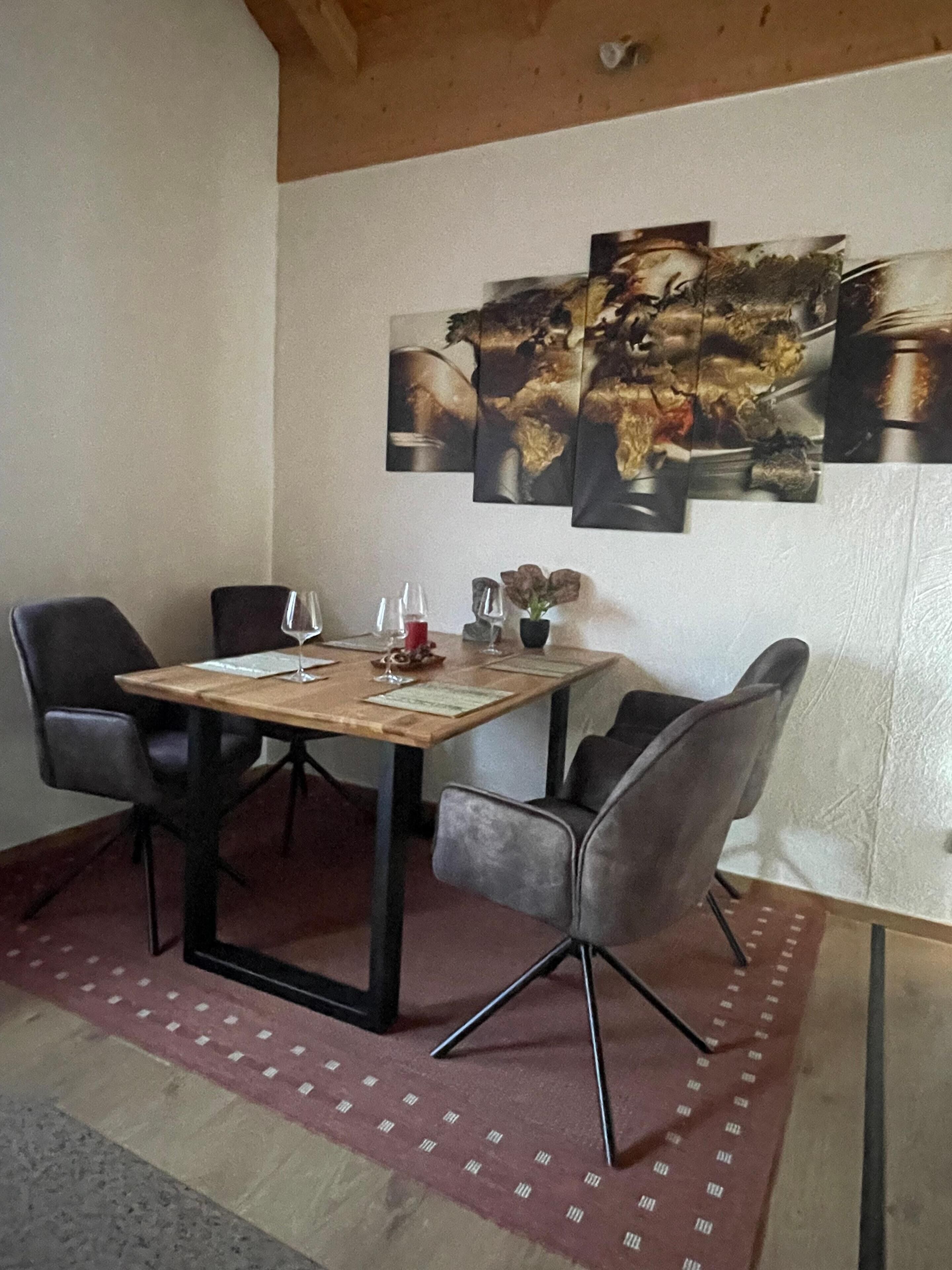 Un coin repas avec une table en bois, quatre chaises et un tapis rouge à motifs.