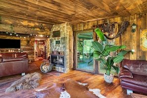 Un interior rústico con chimenea de piedra, sofás de cuero y una planta grande.