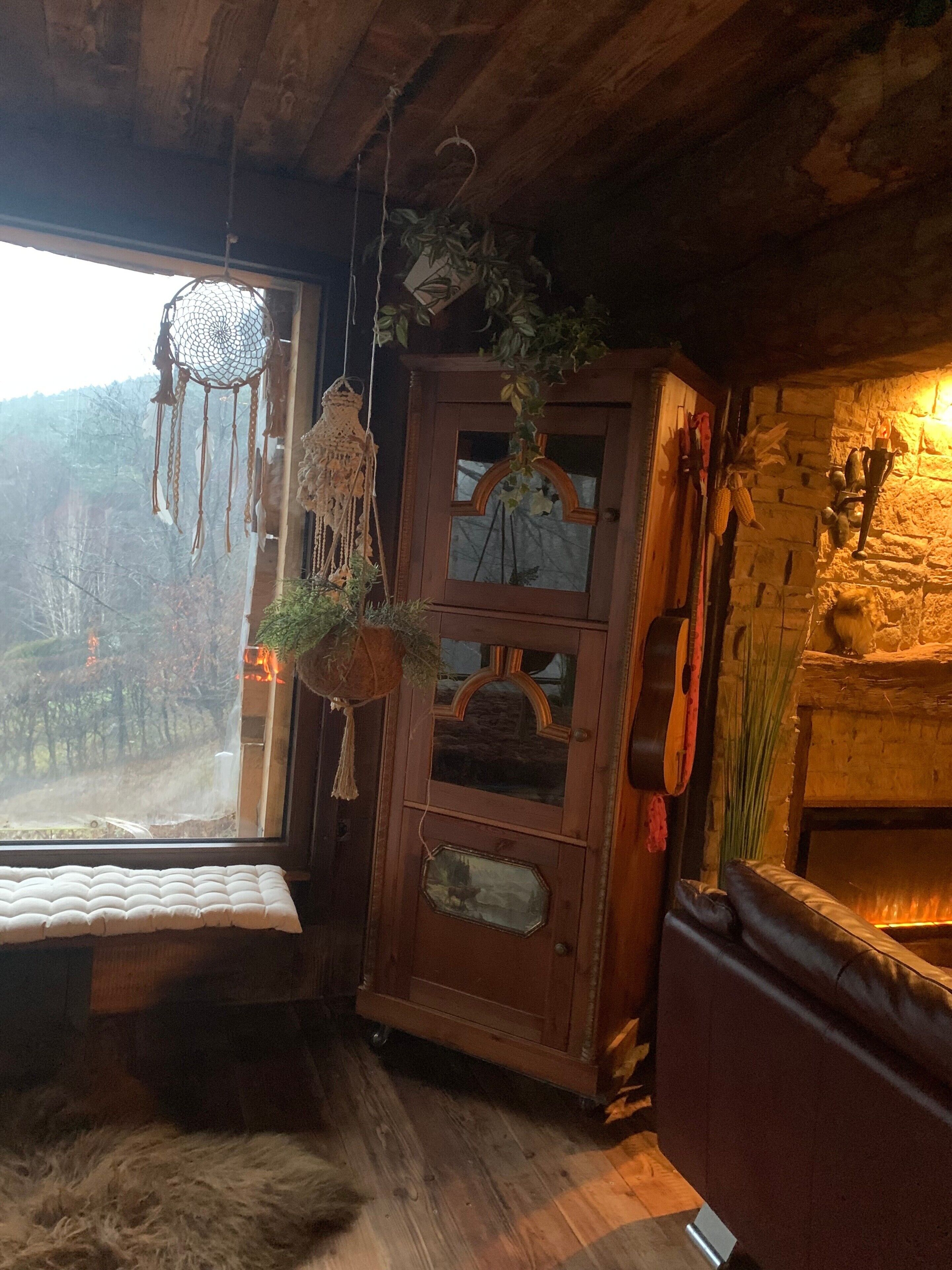 Une pièce rustique avec un plafond en bois, un mur en pierre et une fenêtre donnant sur les arbres.