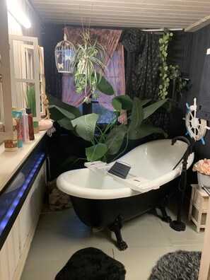 A bathroom with a bathtub, a mirror, a sink, and various plants. - Chalet Hüttenzauber – Nature Retreat with Panoramic Views, Wi-Fi & Pet-Friendly (Dimbach)