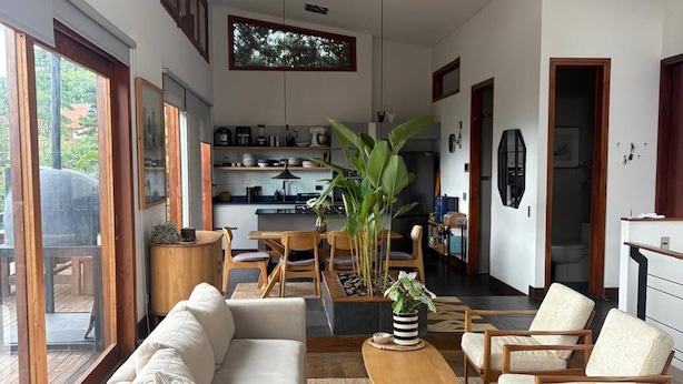 A spacious living area with a sofa, chairs, a coffee table, and a large plant. - Stylish, bioclimatic family house (Envigado)