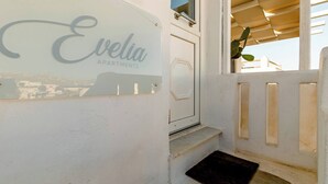 A white exterior wall with a sign reading 'Evelia Apartments.' - Harbor View Apartment in Mykonos Town (Mikonos)
