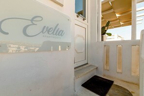 Eine weiße Außenwand mit einem Schild, auf dem 'Evelia Apartments' steht.