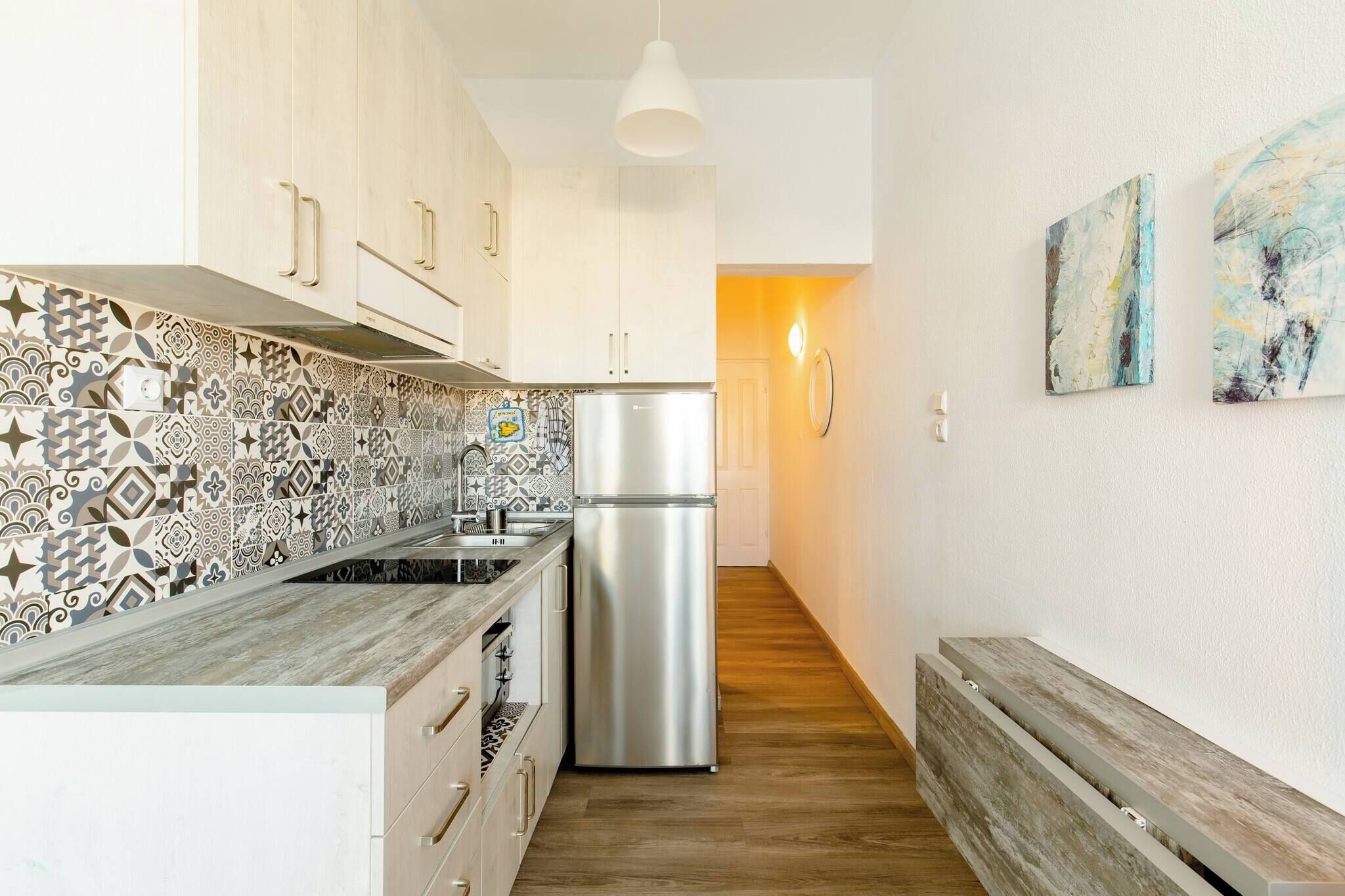 Una cocina moderna con salpicadero estampado, refrigerador de acero inoxidable, armarios de madera y un banco.