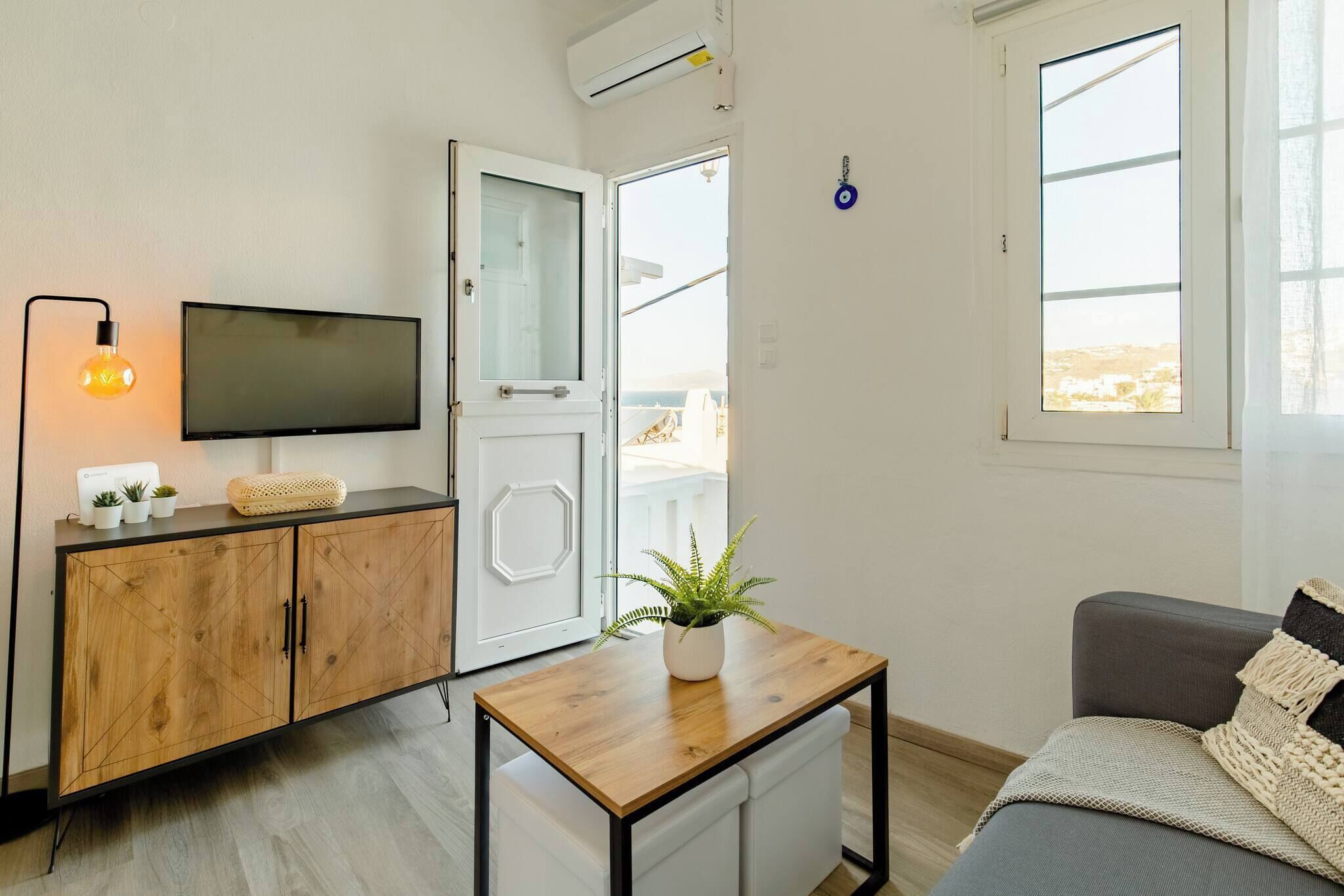 A modern living room with a TV, wooden cabinet, and a small table with a plant.