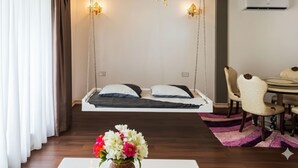 Ein Schlafzimmer mit einem Hängebett, einem Essbereich mit Stühlen und einer Blumenvase auf einem Tisch.