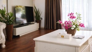 Ein Zimmer mit einem Flachbildfernseher, einem weißen Schrank, einem Korb mit Blumen und einer Topfpflanze.