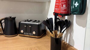 Un plan de travail de cuisine avec un grille-pain, une bouilloire et un extincteur.