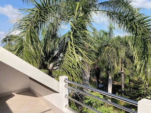 A balcony with a metal railing overlooking a garden with palm trees. - SAMUI SABAI house 4 in the garden with communal pool (Bo Put)