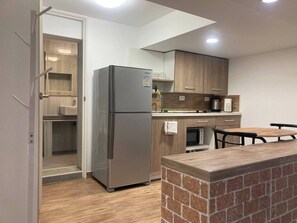 Eine moderne Küche mit Kühlschrank, Holzschränken, einer Mikrowelle und einer Wand mit Ziegeln.