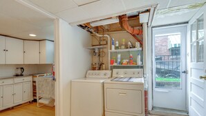 Una sala de lavandería con dos lavadoras, un tendedero y una puerta que da al exterior.