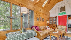 L’intérieur d’une cabane comprend un coin repas, un canapé, une table basse et un panneau indiquant l’emplacement dans le comté de Saratoga.
