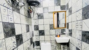 A bathroom with a toilet, sink, mirror, and ceiling fan. - Roomshala Kasa Palace (New Delhi)