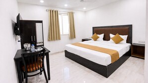 A hotel room with a bed, a desk, a chair, a television, and a window with curtains. - Roomshala Kasa Palace (New Delhi)