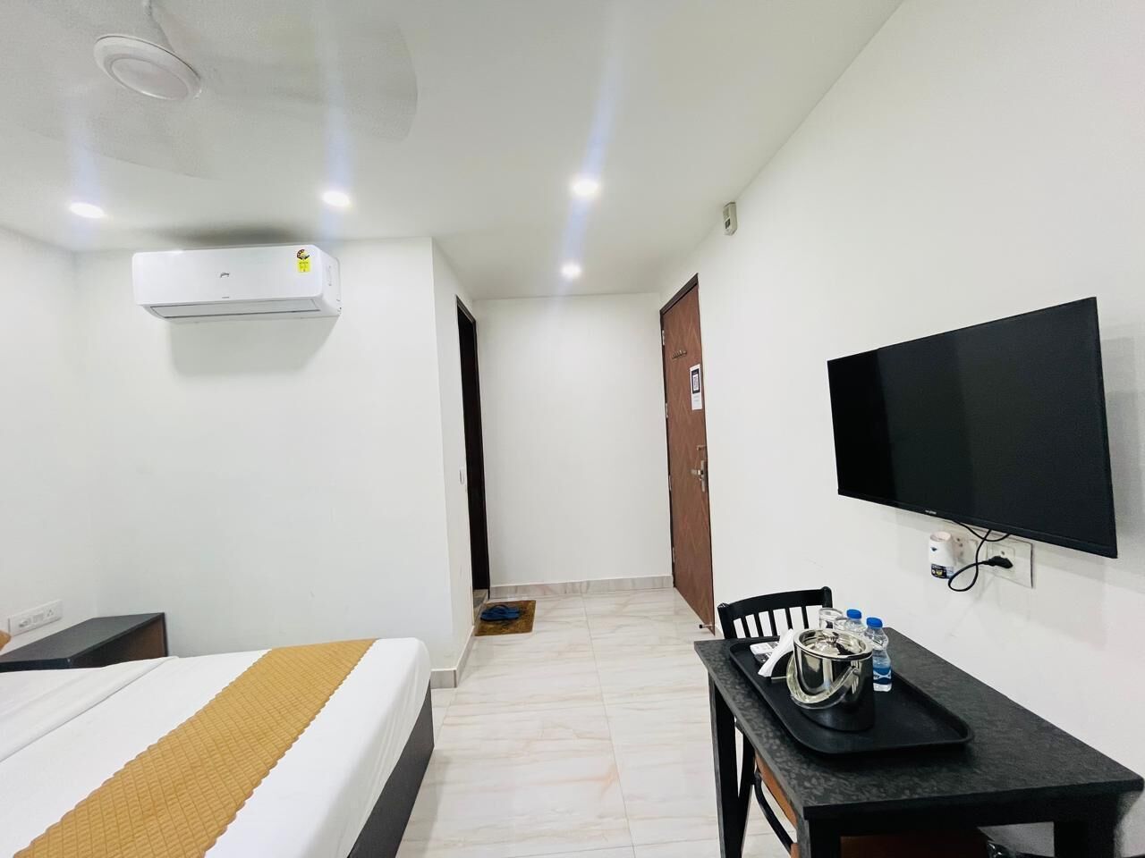 Une chambre d’hôtel comprenant un lit, un bureau avec une chaise, un téléviseur et un appareil de climatisation.