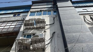 A multi-story building with balconies, visible electrical wires, and a clear blue sky. - Roomshala Kasa Palace (New Delhi)