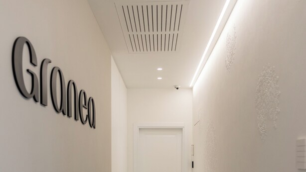 Un pasillo moderno con un letrero 'Grane', una puerta blanca y diseños decorativos en las paredes.