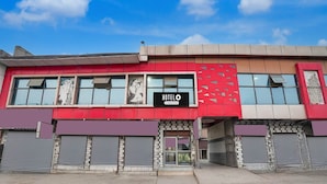A hotel with a red facade, a 'HOTEL' sign, and shuttered storefronts in front. - Hotel O Mathura Janam Bhumi Link Road (Mathura)