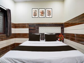 Una habitación de hotel con una cama, un cabecero con diseño estampado y tres cuadros en la pared.